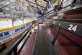An arena interior with a skating rink on the left, and the bleachers on the right.