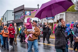 A man holds his young child while walking in a parade in downtown Flin Flon.
