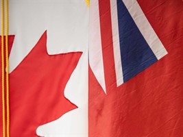 A cropped photo of the Manitoba flag overlapping the Canadian flag